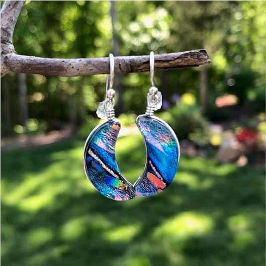 Blue Moon earrings dangling from a branch outside