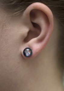 Small dichroic glass stud earrings on a model