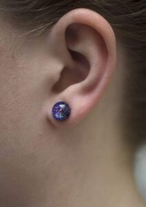 Supernova small purple earrings on a model's ear